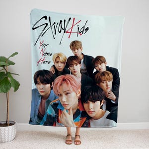Puede incluir: Una manta de franela azul y blanca con un grupo de ocho j&oacute;venes. La manta tiene las palabras "Stray Kids" escritas en negro y rojo. El texto "Your Name Here" est&aacute; escrito en rojo.