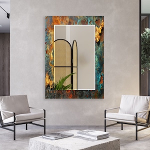 May include: A rectangular mirror with a distressed, rusty, blue, green, and orange frame. The mirror is hanging on a gray wall in a room with two white chairs and a coffee table.