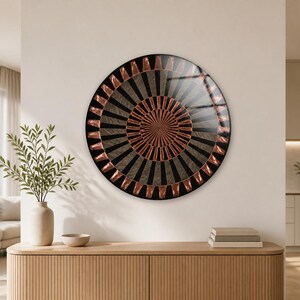 Può includere: Un'opera d'arte murale circolare caratterizzata da un motivo radiale di segmenti alternati neri e color rame metallizzato. Il design presenta una stella centrale in rame circondata da anelli concentrici di forme geometriche scure e lucenti.
