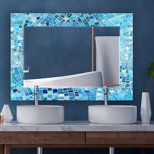 Könnte beinhalten: Zwei weiße Porzellan-Waschbecken mit verchromten Armaturen, die auf einer Holzarbeitsplatte stehen. Ein blauer Mosaikspiegel hängt über den Waschbecken.