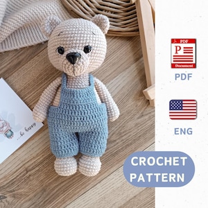 May include: Crochet pattern for a beige amigurumi bear wearing blue overalls. The pattern is available in English and is a PDF download.