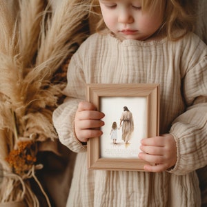 May include: A child holds a framed print of a watercolor painting depicting a man and a young girl walking hand-in-hand. The text below the image reads "For I am the Lord your God, who takes hold of your right hand and says to you, Do not fear; I will help you."