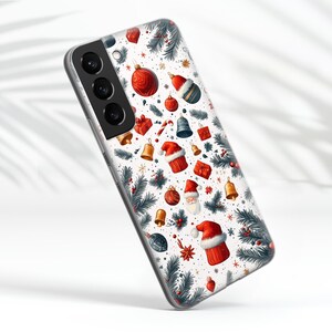 May include: A clear phone case with a white background and a Christmas-themed design. The design features red and green ornaments, Santa Claus, and pine branches.