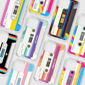 May include: A collection of clear phone cases featuring various cassette tape designs with colorful pride flag patterns. Each case displays text such as A side, You do you, YES, Love wins, GAY STYLE, LESBIAN STYLE, and Transbian printed on the surface.