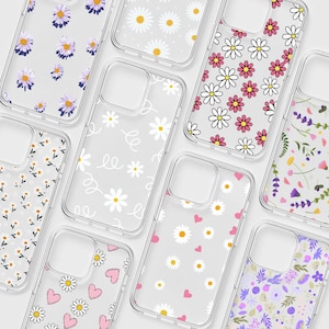 May include: A collection of clear phone cases with various floral designs. Patterns include daisies, hearts, and other flower arrangements in pink, white, purple, and yellow. The cases are made of a transparent material.