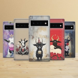 May include: A selection of phone cases with quirky illustrations of goats and a ram. Each case showcases a different design, such as a goat with a cupcake, a goat with a candle, and a black ram wearing a party hat.