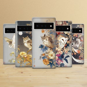May include: Five phone cases with owl illustrations. Each case features a different owl design, with floral and branch accents in shades of brown, yellow, blue, and white. The cases are displayed on a wooden surface against a neutral background.