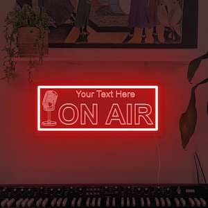 May include: A red neon sign with the words "Your Text Here" and "ON AIR" in white. A microphone graphic is on the left. The sign is rectangular and mounted on a wall. A keyboard is in the foreground.