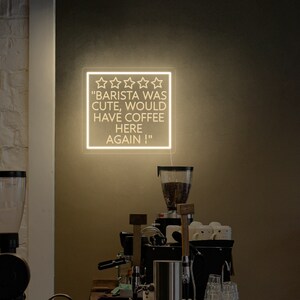 May include: A white neon sign with five stars and the text "Barista was cute, would have coffee here again!"