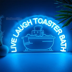 May include: Blue neon sign with the text "Live Laugh Toaster Bath" in a circular shape. The sign features a cartoon image of a bathtub with a smiling toaster inside.