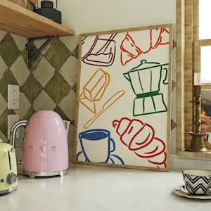 May include: A kitchen with a pink kettle, a yellow toaster, and a framed print of kitchen items. The print features a coffee pot, a croissant, a loaf of bread, and a cup of coffee.