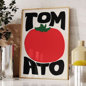 May include: A framed print featuring a red tomato and the word "TOMATO" in black lettering. The letters are stylised and have a retro feel.