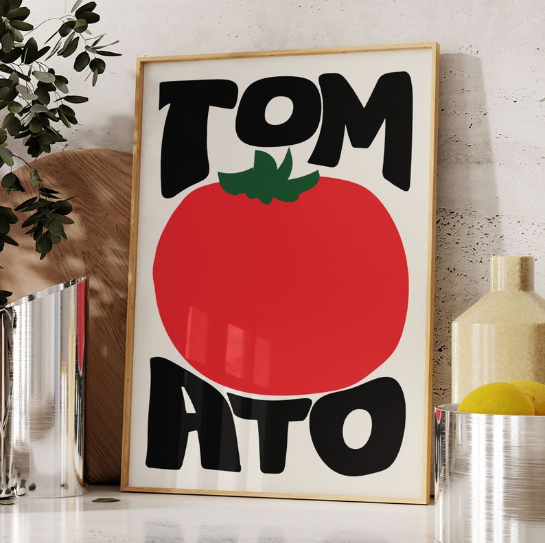 May include: A framed print featuring a red tomato and the word "TOMATO" in black lettering. The letters are stylised and have a retro feel.