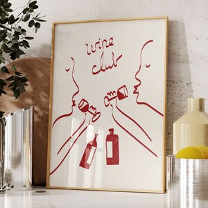 Puede incluir: Una impresi&oacute;n enmarcada blanca con dibujos de l&iacute;neas rojas de dos personas bebiendo vino. El texto "wine club" est&aacute; escrito en cursiva roja.