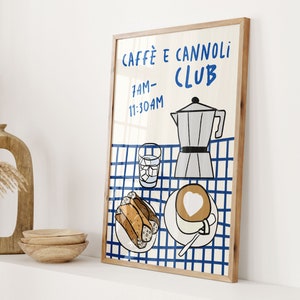 May include: A framed illustration of a blue and white checkered tablecloth with a coffee pot, a glass of ice water, a plate of cannoli, and a cup of coffee with a heart design. The text on the poster reads "Caffe e Cannoli Club 7AM-11:30AM".