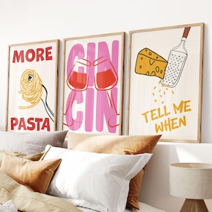 May include: Three framed art prints with food-related themes. One print says "MORE PASTA" with a pasta illustration. Another says "GIN GIN" with two cocktail glasses. The third says "TELL ME WHEN" with cheese and a grater.
