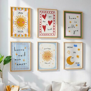 Puede incluir: Seis impresiones art&iacute;sticas enmarcadas con dise&ntilde;os caprichosos. Las impresiones presentan ilustraciones de un sol, corazones, una luna y textos como "Eres tan amado" y "Sue&ntilde;a en grande". Los marcos son de madera clara y la obra de arte tiene una est&eacute;tica alegre y colorida.
