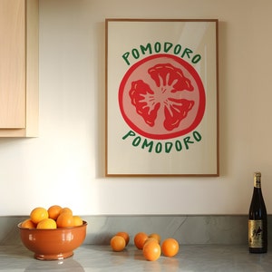 Puede incluir: Una impresi&oacute;n enmarcada con una ilustraci&oacute;n roja y verde de una rodaja de tomate. El texto "POMODORO" est&aacute; escrito en verde arriba y abajo del tomate.