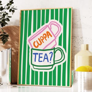 Könnte beinhalten: Ein grün-weiß gestreifter Hintergrund mit zwei bunten Bechern, die übereinander gestapelt sind. Der obere Becher ist rosa mit orangefarbenem Text, der "CUPPA" sagt. Der untere Becher ist grün mit blauem Text, der "TEA?" sagt.