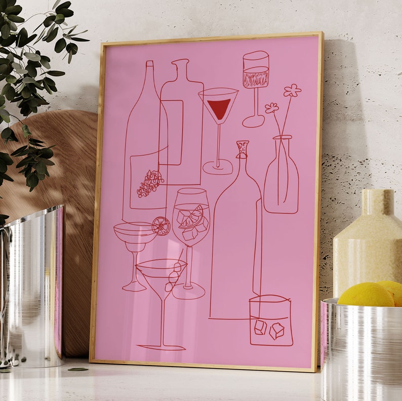 May include: A pink framed print with a red line drawing of various glasses and bottles. The drawing includes a wine glass, a martini glass, a cocktail glass, a wine bottle, and a liquor bottle. The print is on a white background.
