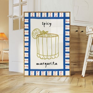 May include: A framed art print featuring a hand-drawn illustration of a spicy margarita cocktail. The artwork has a white background with a blue and red border. The words "spicy" and "margarita" are written in black.
