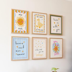 Puede incluir: Seis impresiones art&iacute;sticas enmarcadas con ilustraciones y texto caprichosos. Las impresiones presentan un sol sonriente, un pato amarillo y frases como "Home is with you". Los marcos son de madera clara.