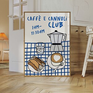 May include: A framed illustration of a cafe menu with the text "Caffe e Cannoli Club" and the hours "7AM-11:30AM". The illustration features a blue and white checkered tablecloth with a coffee pot, a glass of ice water, a plate of cannoli, and a cup of cappuccino.