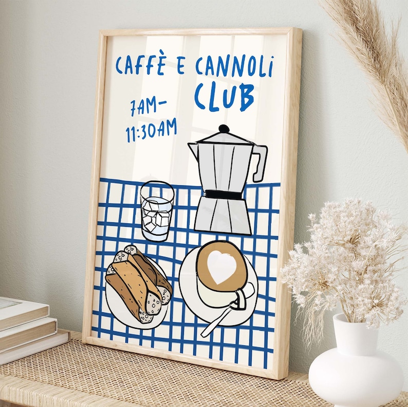 May include: A framed illustration of a blue and white checkered tablecloth with a coffee pot, a glass of water, a plate of cannoli, and a cup of cappuccino. The text "Caffe e Cannoli Club" and "7AM-11:30AM" is printed on the illustration.