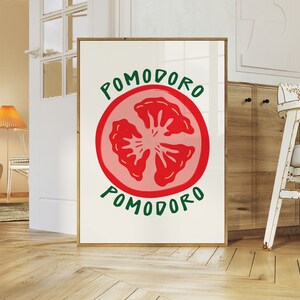 Puede incluir: Un p&oacute;ster enmarcado blanco con una ilustraci&oacute;n de rodaja de tomate roja y el texto "POMODORO" en letras verdes.
