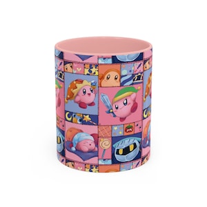 Puede incluir: Una taza cilíndrica de cerámica con interior y borde de color rosa claro. El exterior presenta un colorido patrón de retazos con varios personajes de dibujos animados, incluida una criatura redonda rosa con diferentes sombreros, una espada y una máscara plateada.