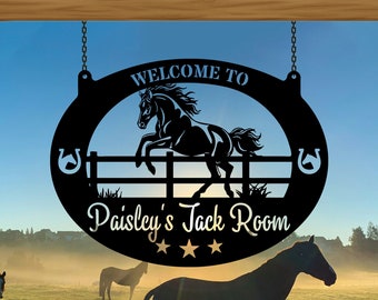 May include: Black metal sign with a silhouette of a horse jumping over a fence. The sign reads "Welcome to Paisley's Jack Room" with three stars below the text.