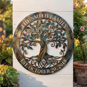 Puede incluir: Un letrero de pared circular de metal con un diseño de árbol de la vida con ramas y hojas detalladas. El anillo exterior muestra el texto THE SMITH FAMILY en la parte superior y EST. OCTOBER 20, 2018 en la parte inferior con acabado patinado.
