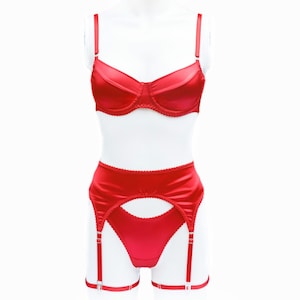 May include: A red satin lingerie set, including a bra with adjustable straps and a garter belt with matching thong. The bra has underwire support and a scalloped edge. The set is displayed on a white mannequin.
