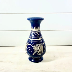 May include: A blue ceramic vase with white painted designs. The vase has a rounded body and a narrow neck.