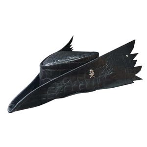 Könnte beinhalten: Ein schwarzer Piratenhut aus Leder mit einer Totenkopf- und Knochen-Anstecknadel. Der Hut hat eine breite Krempe und eine spitze Krone mit zwei Flügeln an jeder Seite.