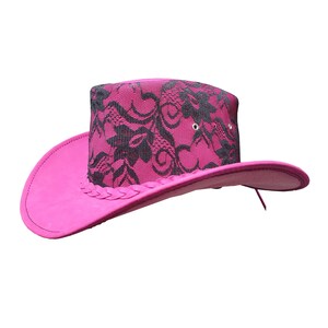 Könnte beinhalten: Ein rosa Cowboyhut mit einem schwarzen Spitzenmuster auf der Krone.