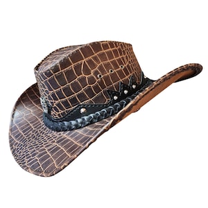 May include: A brown leather cowboy hat with a crocodile pattern and a black braided band with silver studs.