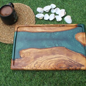 May include: A rectangular wooden serving tray with a green epoxy resin inlay. The tray has a natural wood finish and is perfect for serving appetizers, cheese, or charcuterie.