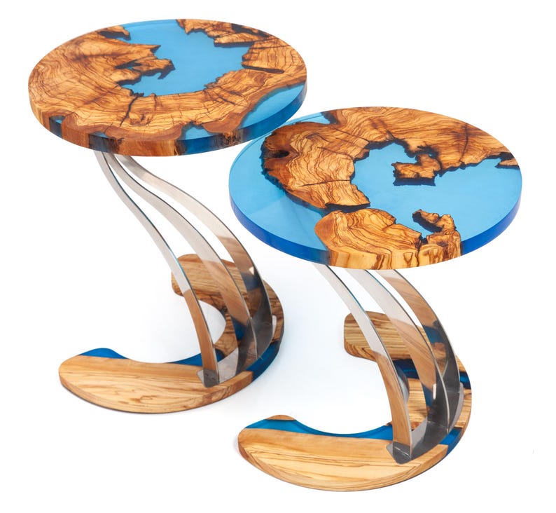 K&ouml;nnte beinhalten: Zwei runde Holz-Beistelltische mit blauen Harzeinlagen und einem einzigartigen, wellenf&ouml;rmigen Edelstahlfu&szlig;.