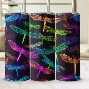 May include: Three stainless steel tumblers with a black background and a colorful dragonfly pattern. The dragonflies are outlined in neon colors and are arranged in a repeating pattern.