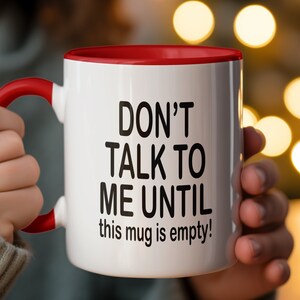 May include: White ceramic mug with a red rim and handle. The mug has black text that reads "Don't talk to me until this mug is empty!"