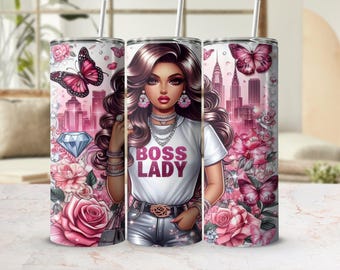 May include: A stainless steel tumbler with a pink and white design featuring a woman with long brown hair, a white shirt with the text "Boss Lady" in pink, and a cityscape in the background. The tumbler is decorated with pink flowers, butterflies, and a diamond.