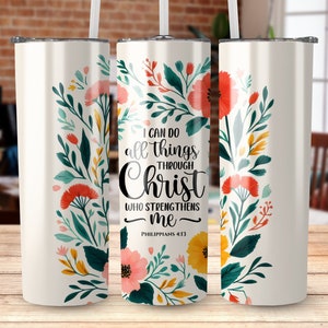 Op de afbeelding: Een witte roestvrijstalen beker met een bloemenpatroon en de tekst "Ik kan alles door Christus, die mij kracht geeft - Filippenzen 4:13".