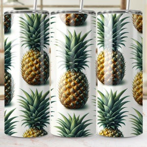 May include: A set of three stainless steel tumblers with a repeating pattern of detailed pineapples. The pineapples are golden yellow with green leafy tops, set against a white background. Each tumbler has a silver lid and straw.