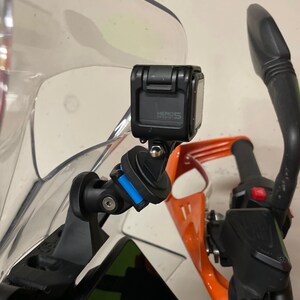 May include: A black GoPro HERO5 action camera mounted on a motorcycle handlebar using a black and blue mount.