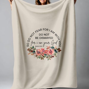 Puede incluir: Una manta de franela beige con un diseño floral y el texto "So do not fear for I am with you. Do not be dismayed for I am your God. Isaiah 41:10"