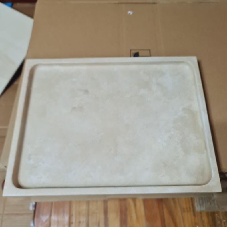 Puede incluir: Una bandeja rectangular beige con un borde ligeramente elevado. La bandeja tiene una superficie texturizada y una paleta de colores neutros, adecuada para varios estilos de decoraci&oacute;n del hogar. La bandeja est&aacute; hecha de un material s&oacute;lido.
