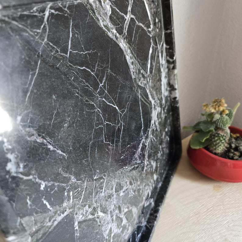 Op de afbeelding: Een rechthoekig dienblad met een donkerzwart oppervlak en opvallende witte aders die het uiterlijk van natuurlijk marmer nabootsen. Het dienblad heeft opstaande randen en een gladde, reflecterende afwerking met een contrastrijk patroon.