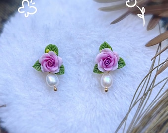 May include: A pair of delicate earrings featuring pink rose flower accents and pearl drops.