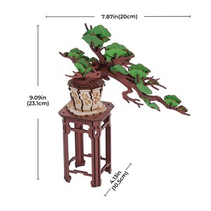 May include: A wooden model of a bonsai tree with green leaves, sitting on a brown wooden stand. The tree is 7.87 inches (20 cm) tall and the stand is 4.13 inches (10.5 cm) tall.
